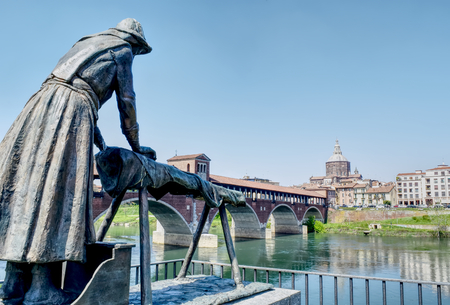 The laundress statue on the bank of the river Ticino with the city on the background in Pavia, Italy. HDR effect.の写真素材