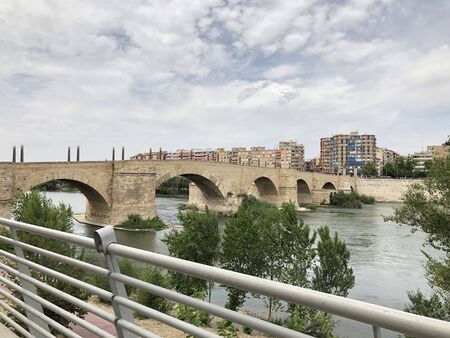 The Ebro river and the old Stone Bridge of Zaragoza in Spain, in a cloudy dayの写真素材
