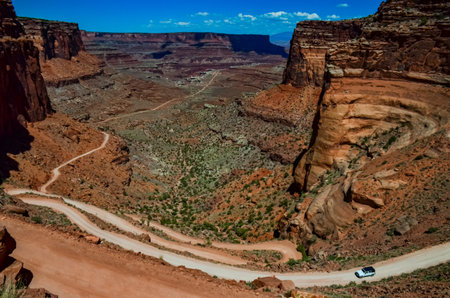 Dirt road at the bottom of the canyon among the layered geological formations of red rocks. USA