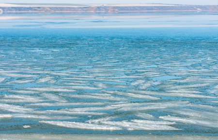 Ice floating near the shore in the form of oblong ice floes, rolled around by waves and a storm in...