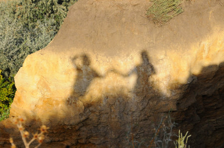 Shadow on yellow clay of two people holding handsの写真素材