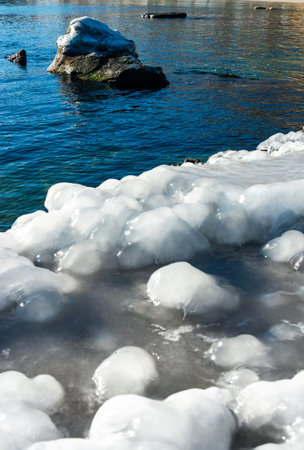 Icing of a concrete pier in the Black Sea, blocks of melted ice glisten in the sun, ice by the sea,...