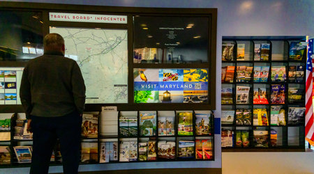 Maryland, USA - November 02, 2025: This is a visitor information center at the Maryland House Travel Plaza, featuring a Travel Board with digital maps and racks of brochures. The area includes backlit panels for advertisements, interactive screens for d