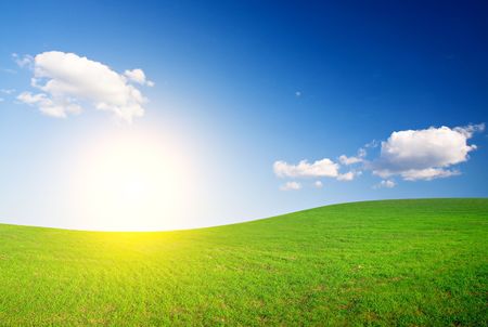 Green hill under blue cloudy sky whit sunの写真素材