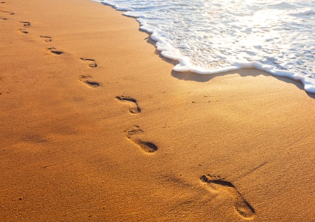 beach, wave and footsteps at sunset timeの写真素材