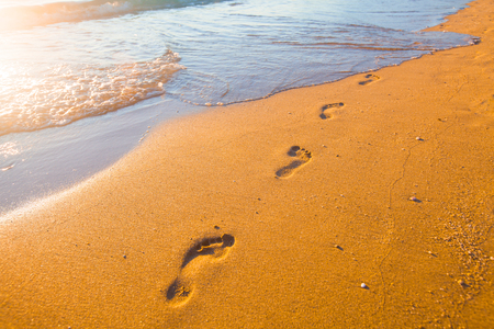 beach, wave and footprints at sunset timeの写真素材