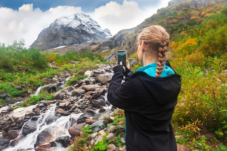 woman taking a photo of mountin on smartphoneの写真素材