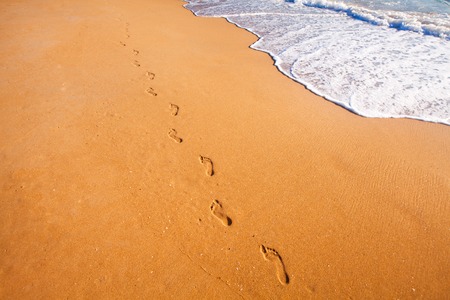 beach, wave and footprints at sunset timeの写真素材