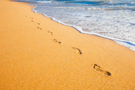 beach, wave and footprints at sunset timeの写真素材