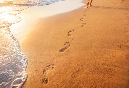 beach, wave and footprints at sunset timeの写真素材