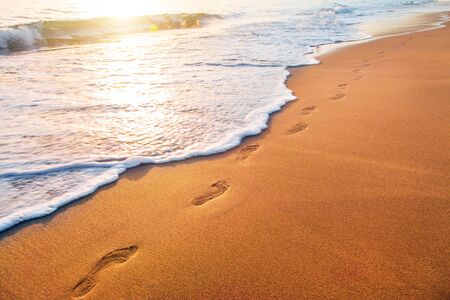 beach, wave and footprints at sunset timeの写真素材