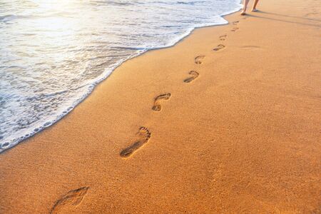 beach, wave and footprints at sunset timeの写真素材