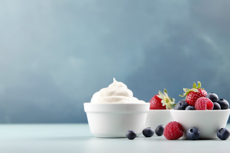 Bowl of yogurt with fresh strawberries and blueberries on a light background.の素材