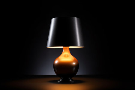 A modern table lamp illuminated against a dark backgroundの素材