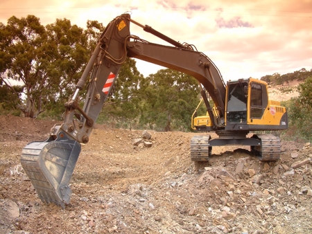 Skidsteer Excavator at work moving and digging dirt with soil earth works construction in new housing development subdivision.  Earth mover bucket excavation landscaping dam and large hole fillingの写真素材
