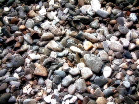 Filtered abstract Pebble, Rock, Stone Background in Shallow Water Rock Pool with sun streaming into clear seaside waterの写真素材