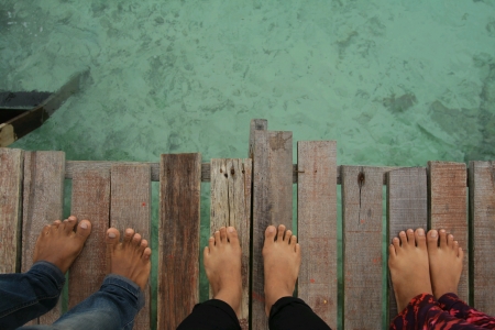 Top view of foot standing in front of clear sea waterの素材