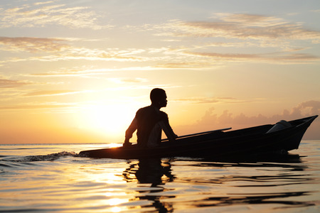 Local sea gypsy boating across open sea water with beautiful sunset background の写真素材