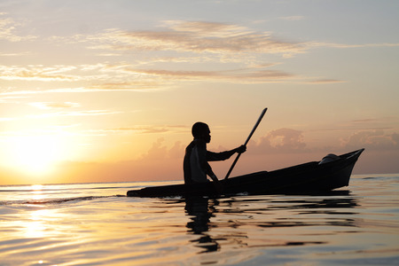 Local sea gypsy boating across open sea water with beautiful sunset background の写真素材