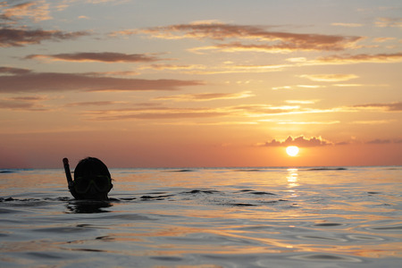 man swimming on open sea water with sunset backgroundの写真素材