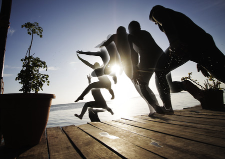 silhouette of a man jumping from a balcony to open sea water in combined image sequenceの写真素材