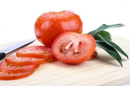 tomatoes cut by a kitchen knife on a wooden boardの写真素材