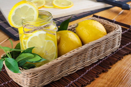 lemonade with some fresh uncut yellow lemon in wooden kitchen tableの写真素材