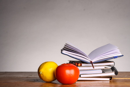 notebooks with lemon and tomato in front on gray backgroundの写真素材