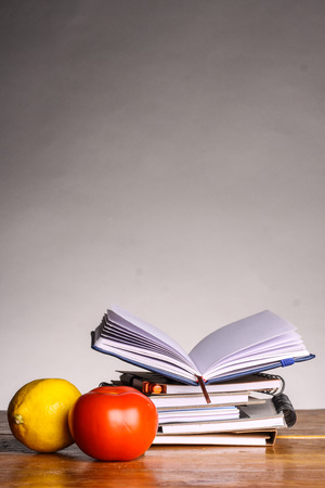 notebooks with lemon and tomato in front on gray backgroundの写真素材