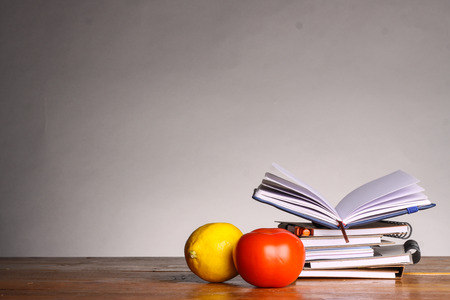 notebooks with lemon and tomato in front on gray backgroundの写真素材
