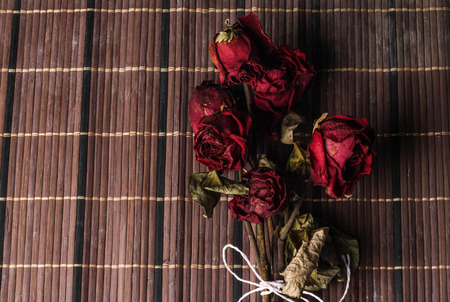 red dried rose bouquet being tied with rope. Isolated on wooden backgroundの写真素材