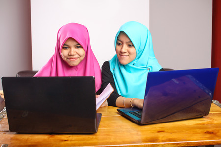 two young muslim women doing a group discussion by using a laptopの写真素材