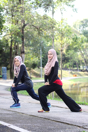 two young muslim women is stretching her body before they jogging in the morning.の写真素材