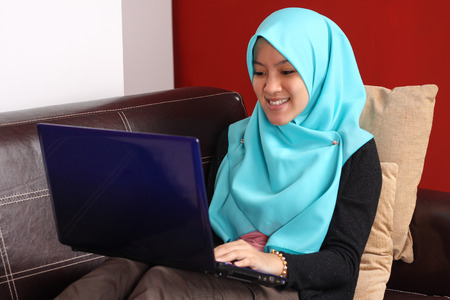 young muslim women relaxing on the sofa with laptopの写真素材
