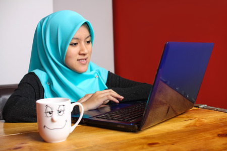 young muslim women drinking a coffee while using laptopの写真素材