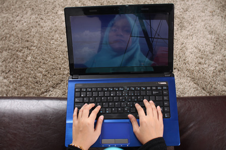 Close-up Of Young muslim Woman Using Laptop On Couchの写真素材