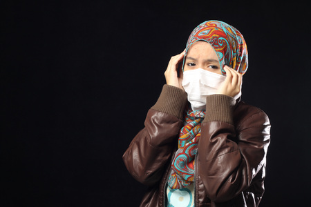 muslim woman wearing disposable face mask on black background.の写真素材