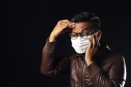 asian man wearing disposable face mask on black background.の写真素材