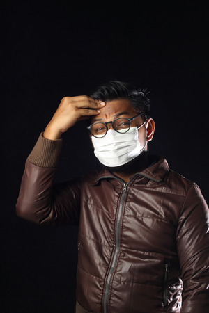 asian man wearing disposable face mask on black background.の写真素材