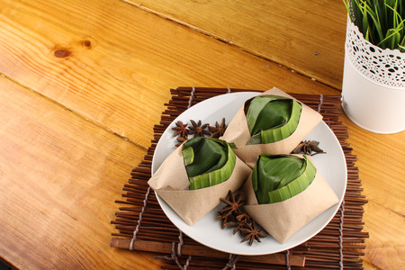 traditional fresh Malaysian nasi lemak packed with banana leaf in wood backgroundの写真素材