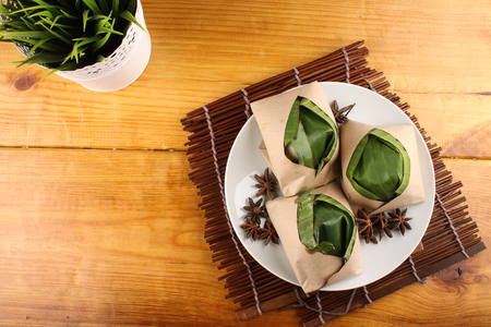 traditional fresh Malaysian nasi lemak packed with banana leaf in wood backgroundの写真素材
