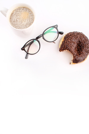 chocholate doughnuts been eaten concept with spectacles and a hot drink in the frameの写真素材