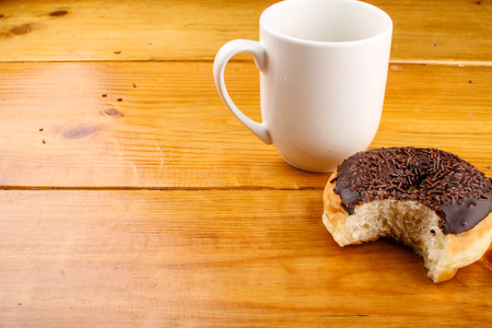 eaten chocholate doughnut with a hot drink in wood backgroundの写真素材