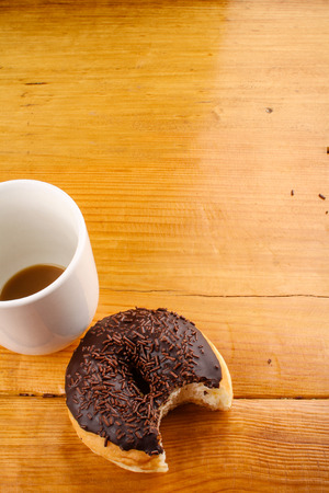 eaten chocholate doughnut with a hot drink in wood backgroundの写真素材