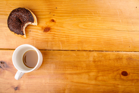 eaten chocholate doughnut with a hot drink in wood backgroundの写真素材