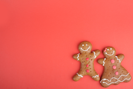Gingerbread man and Gingerbread lady decorated colored icing. Holiday cookie in shape of man and lady in red backgroundの写真素材