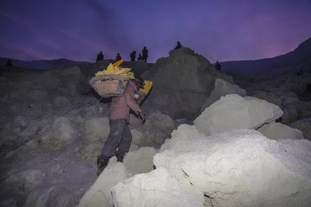 IJEN, INDONESIA - November 18 : A Penambang at Ijen crater carrying raw sulfur stone to local dealer. Sulfur mining is one of the main income for the local at Ijen crater 18 November 2015のeditorial素材