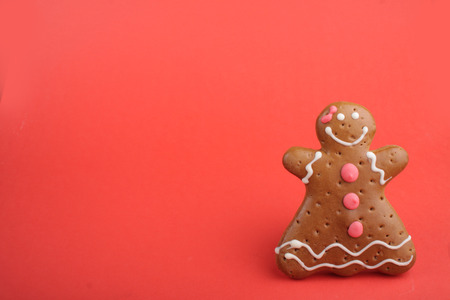 Gingerbread lady decorated colored icing. Holiday cookie in shape of  lady in red backgroundの写真素材