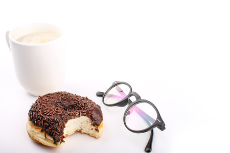 chocolate doughnut been eaten concept with spectacles and a hot drink in the frameの写真素材