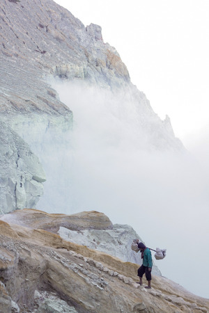 IJEN, INDONESIA - November 18 : A Penambang or Pengangkut Beliran at Ijen crater carrying raw sulfur stone to local dealer. Sulfur mining is one of the main income for the local at Ijen crater 18 November 2015のeditorial素材